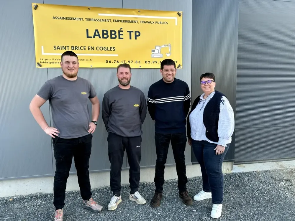 Photo de l'équipe devant une bâche jaune siglée